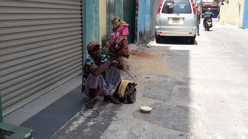 Man holding monkey while crouching on street