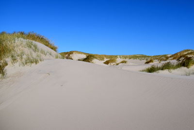 Scenic view of desert against clear blue sky