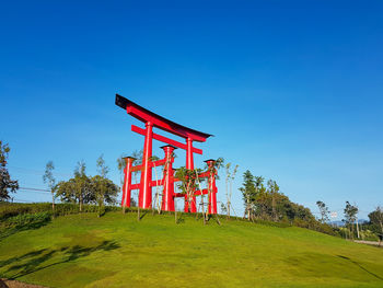 Traditional torii on field against clear blue sky