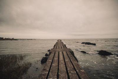 Surface level of pier over sea against sky