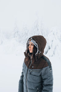 Woman wearing hat standing against snow