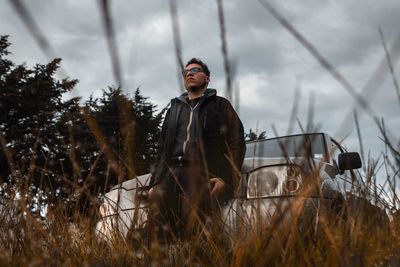 Man standing by pick-up truck on field