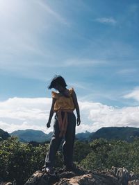 Rear view of man standing on mountain against sky