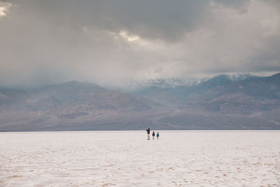 People walking on desert against sky