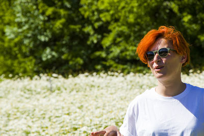 Women with sunglasses in field of daisy flowers during sunlight