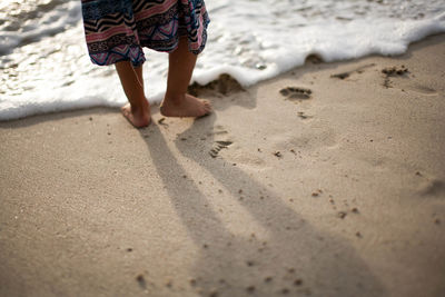 Low section of woman standing at beach