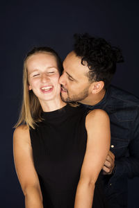 Portrait of a smiling young couple against black background