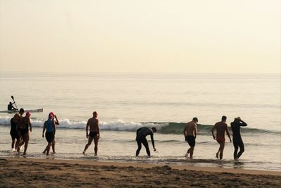 People enjoying at seaside against clear sky