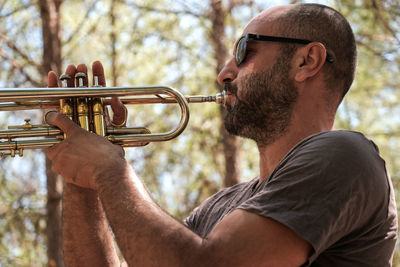 Side view of man playing trumpet outdoors