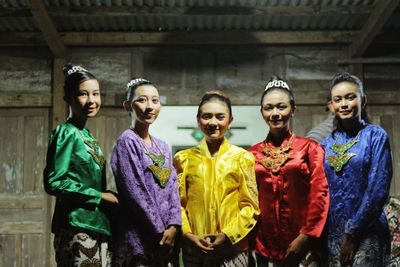 Portrait of smiling women wearing colorful traditional clothing while standing against house at night