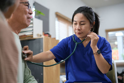 Side view of young woman applying make-up at home