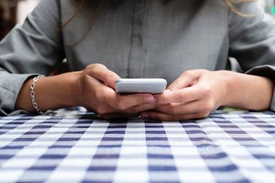Close-up of woman using mobile phone on table