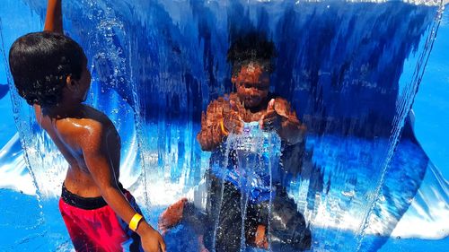Rear view of shirtless man swimming in pool