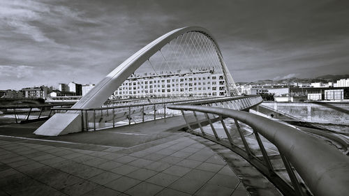 View of bridge in city against cloudy sky