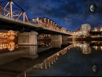 Arch bridge over river against sky in city at night