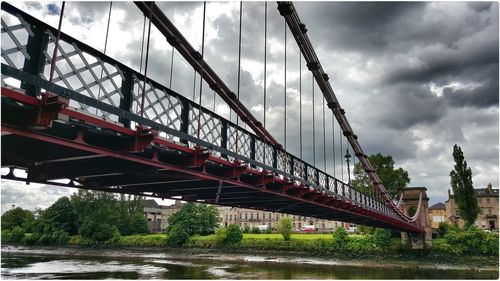 Low angle view of bridge over river against cloudy sky