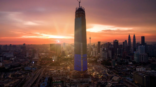 Modern buildings in city against sky during sunset