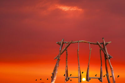 Swing and sunset on evening over silhouette birds flying on the red orange sky and dark cloud