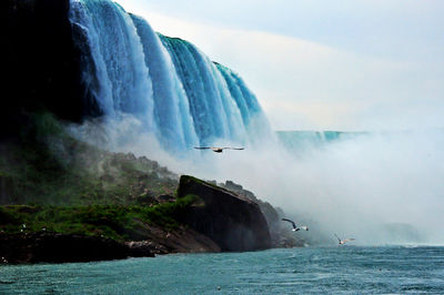 Scenic view of waterfall sea against sky