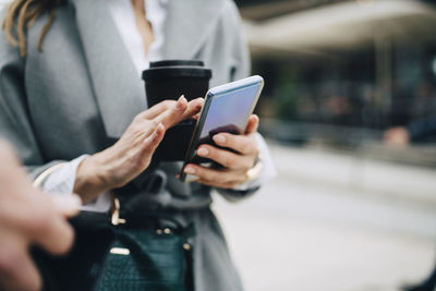 Midsection of businesswoman using phone in city