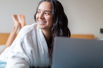 Portrait of young woman sitting on bed at home