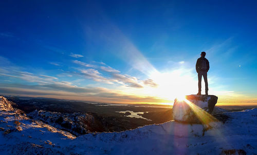 Man standing on snowcapped mountain against sky during winter