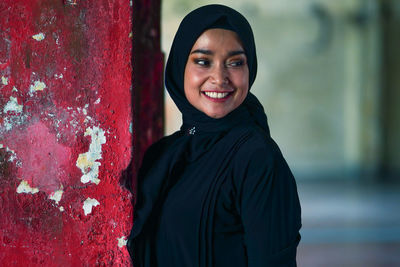 Beautiful indonesian woman wearing a black hijab against the rustic wall as a background