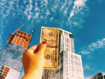 Low angle view of cropped hand against clear sky