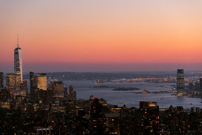 Illuminated buildings in city against sky during sunset