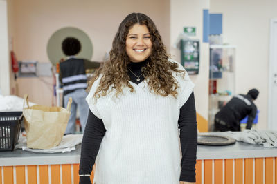 Portrait of happy female worker standing at recycling center