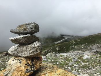 Stack of stones on rock against sky