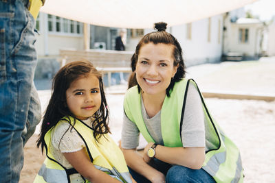 Portrait of smiling female teacher with student in playground against school building