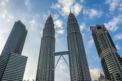 Low angle view of skyscrapers against cloudy sky