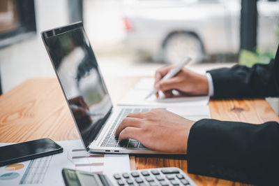 Midsection of businessman using laptop on table