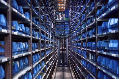 Worker operating high rack in storehouse