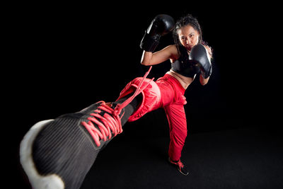 Midsection of woman with arms raised against black background