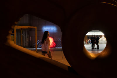 Rear view of people walking in illuminated corridor