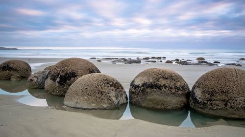 Scenic view of beach against cloudy sky