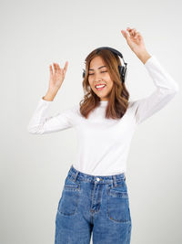 Smiling young woman standing against white background