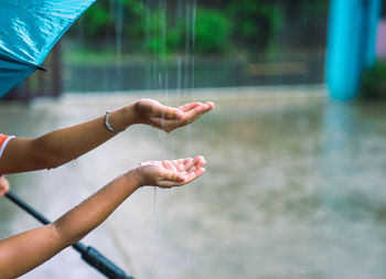 Raindrops splashing on cropped hands