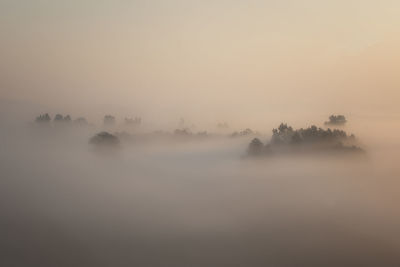 Scenic view of landscape against sky at foggy weather