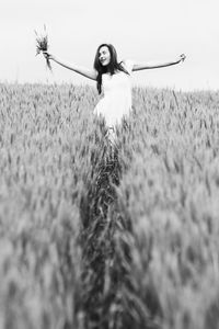 Portrait of young woman on field against sky