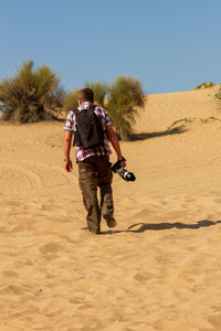 Rear view of man walking at desert