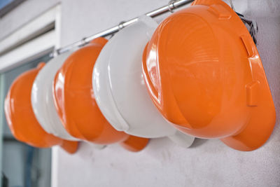 Close up hard hats hanging on hook against the dirty white wall.