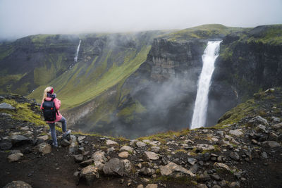 Woman with backpack enjoying haifoss waterfall of iceland highlands in thjorsardalur valley
