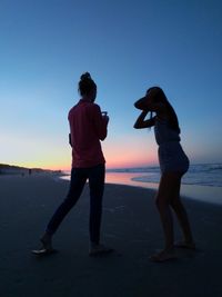 Rear view of people photographing sea against clear sky