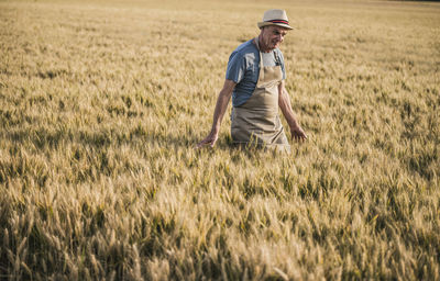 Senior farmer wearing hat walking in field