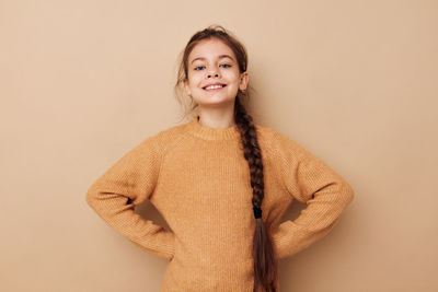 Portrait of young woman standing against pink background