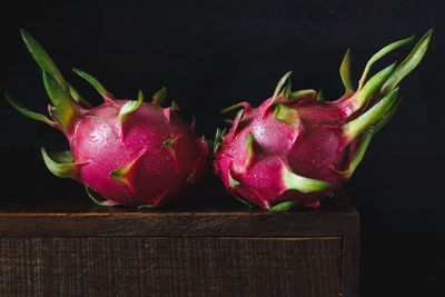 Close-up of wet dragon fruits on wood against black background