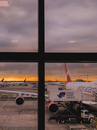 Airplane on runway against sky during sunset